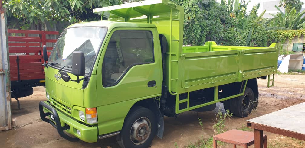 Green lorry with a high-sided steel cargo body and a side ladder