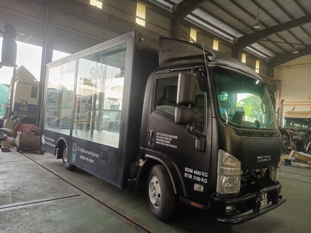 Black Isuzu truck with a glass-sided display body