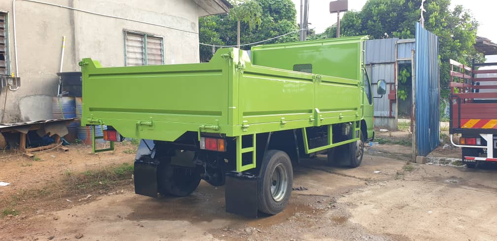 Green lorry with a steel cargo body, seen from the rear