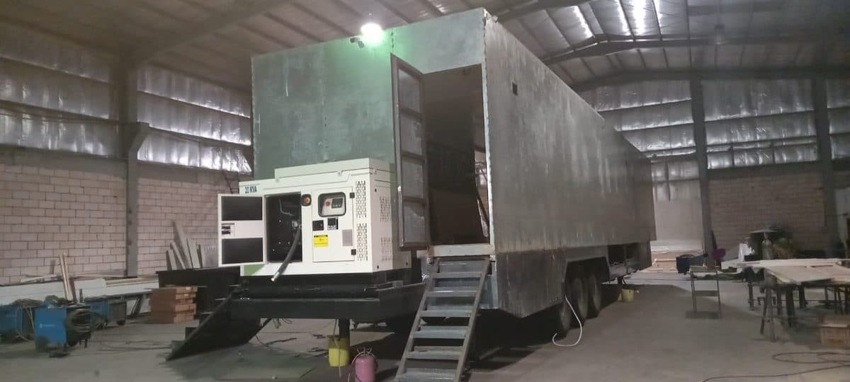 Large exhibition trailer body with a generator and steps, inside the workshop