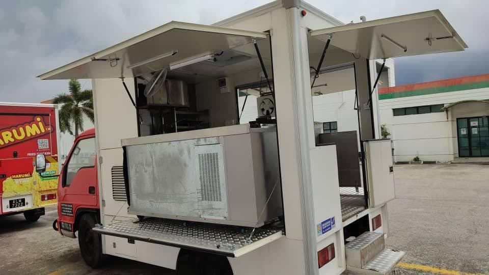 Food truck with side and rear hatches open and kitchen equipment inside